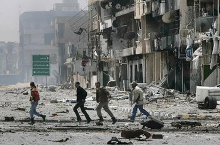 Những chiến binh đối lập chạy qua một đường phố tạiMisrata trong đợt pháo kích của quân chính phủ Libya hôm 23/4.